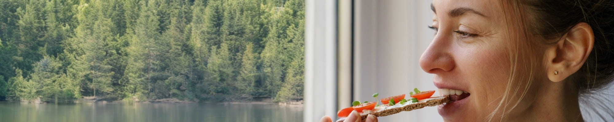 Frau beißt in ein Knäckebrot mit Microgreens und Tomaten