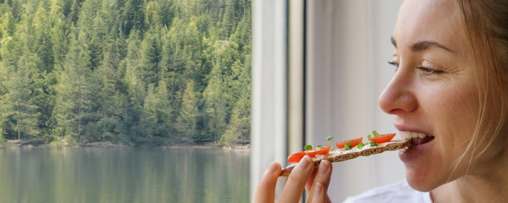 Frau beißt in ein Knäckebrot mit Microgreens und Tomaten
